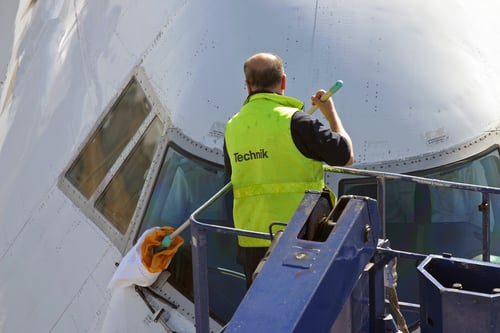 man cleaning the window of an airplane cockpit