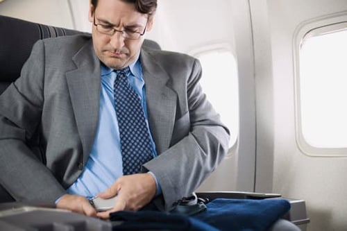 man putting on seatbelt on an airplane